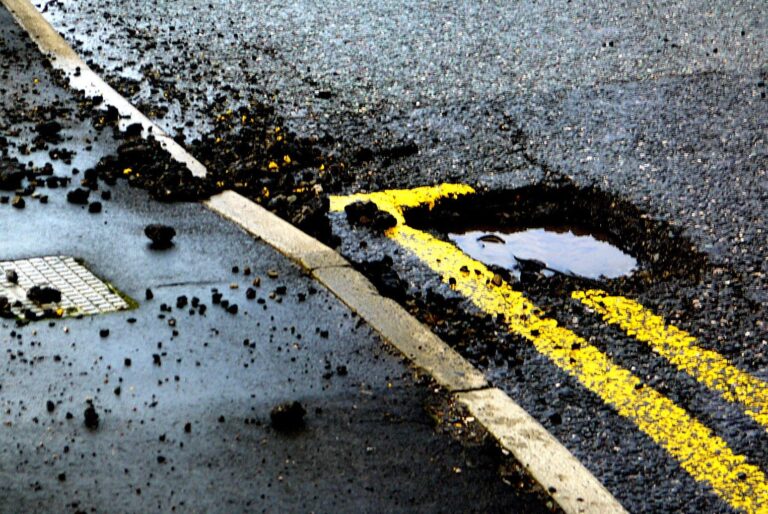 Road infrastructure problems in Pakistan shown by potholes and surface damage caused by poor drainage